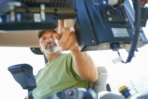 Shot of a farmer working inside the cab of a modern tractor